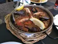 Paella marinera con gambas y mejillones, un plato típico de los restaurantes de Blanes, servida en una paellera sobre una cesta de mimbre.