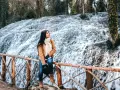 Joven admira la cascada en el Monasterio de Piedra, Zaragoza. El agua cae en cascada sobre rocas cubiertas de musgo, creando un paisaje natural impresionante.