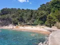 Aguas cristalinas y arena dorada en Cala d'en Carlos, con un chiringuito y pinos frondosos.
