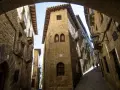 Calle empedrada con edificios de piedra, balcones de hierro y un arco. Un lugar que evoca la historia de los Reyes Católicos.
