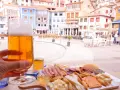 Disfrutando de una cerveza y una tabla de quesos y embutidos en Cudillero, con las coloridas casas de fondo.