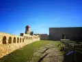 Impresionante castillo de piedra con murallas, arcos y torreón. Un lugar histórico que ver en Benabarre, bajo un cielo azul intenso.