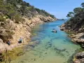 Una cala idílica en Tossa de Mar con aguas cristalinas, rocas escarpadas y un pequeño bote.