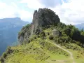 Pequeña ermita de piedra con tejado cónico, rodeada de vegetación y un sendero que sube por la ladera. Las ermitas de Tella se alzan majestuosas.