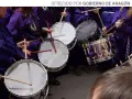 Tambores resonando, parte de las tradiciones de Aragón. Nazarenos con túnicas moradas golpean los parches en una procesión.