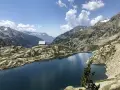 Un refugio solitario junto a los ibones de Bachimaña, rodeado de montañas rocosas y un lago azul intenso bajo un cielo despejado.