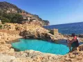 Piscinas naturales de Begur, con aguas cristalinas y rocas doradas. Un hombre contempla el mar azul.