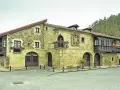 Edificio histórico de piedra con balcones de madera, ideal para saber donde comer en Lierganes.