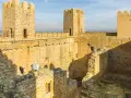 El castillo de Sádaba, con sus imponentes torres de piedra dorada, se alza bajo un cielo azul, invitando a imaginar batallas y leyendas.