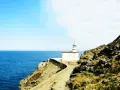 El faro de Cala Nans se alza sobre un acantilado rocoso, vigilando el azul intenso del mar Mediterráneo bajo un cielo despejado.