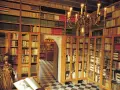 Interior del museu del castell de Peralada, con estanterías repletas de libros antiguos y una lámpara de araña dorada.
