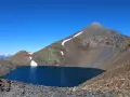 Lago azul profundo en el collado de Tebarray, rodeado de montañas rocosas y con restos de nieve.