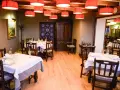 Mesas puestas y listas para comer en Morella. El restaurante tiene lámparas rojas, muebles de madera oscura y un cuadro en la pared.