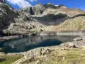 Un lago de montaña de aguas azules profundas, reflejando las cumbres rocosas y el cielo. Un paisaje perfecto para la ruta ibones azules.