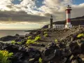 Faros gemelos en la costa rocosa, un destino que ver en La Palma. El mar y el cielo nublado completan la escena.