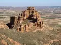 Impresionante formación rocosa en Villarroya de la Sierra, con un paisaje de campos cultivados al fondo.