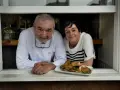Chef y camarera sonríen tras ventana con plato de setas. Descubre dónde comer en Castro Urdiales.
