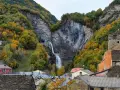 Cascada espectacular en Broto, Huesca, rodeada de bosques otoñales y casas de piedra.