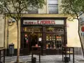 Fachada de "Hijos de E. Morales", un bar tradicional en Sevilla, con mesas en la acera y botellas expuestas.