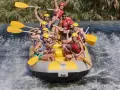 Un grupo de personas disfruta del rafting, remando con entusiasmo en una balsa amarilla sobre aguas turbulentas. ¡Una aventura emocionante!
