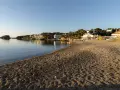La platja gran de Cadaqués, con casas blancas y kayaks coloridos, se baña en la calma del mar al atardecer.