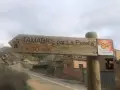 Señal de madera en albelda huesca: "Tamarite por La Penella, 1h 30 min". Al lado, señal de rutas ornitológicas.