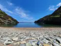 Cala Sa Sabolla, una bahía rocosa con aguas cristalinas y un velero solitario.
