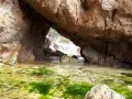 Entrada a la cala del crit, con rocas y algas verdes en el agua cristalina.