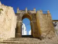 Antigua puerta de Medina Sidonia, con escalinata de piedra y cielo azul. Merece la pena visitar Medina Sidonia.