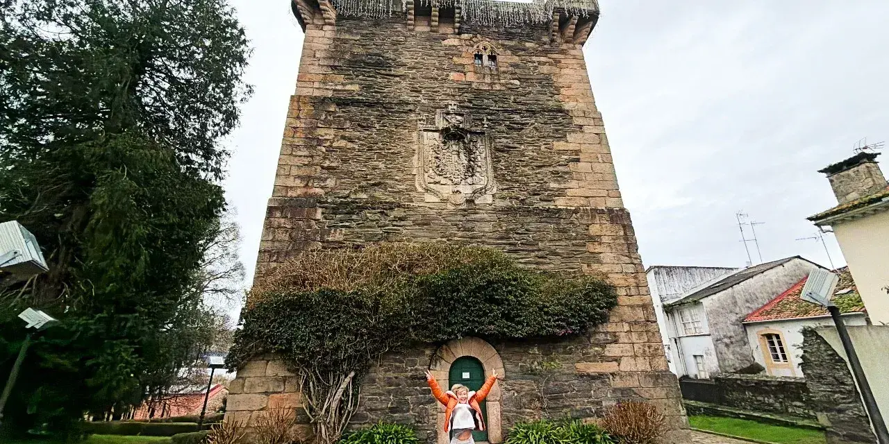 Persona salta de alegría frente a la Torre de los Andrade, un lugar imprescindible que ver en Pontedeume.