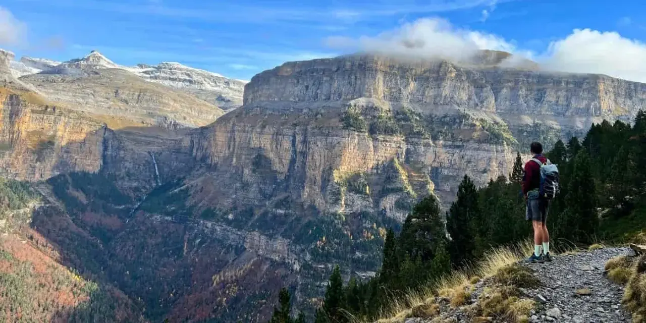 Senderista admira el imponente paisaje de los Pirineos. Las **rutas Pirineos** ofrecen vistas espectaculares de cañones y cascadas.