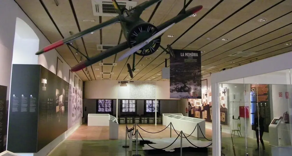 Interior del museo de la Batalla del Ebro, con un avión colgado del techo y expositores.
