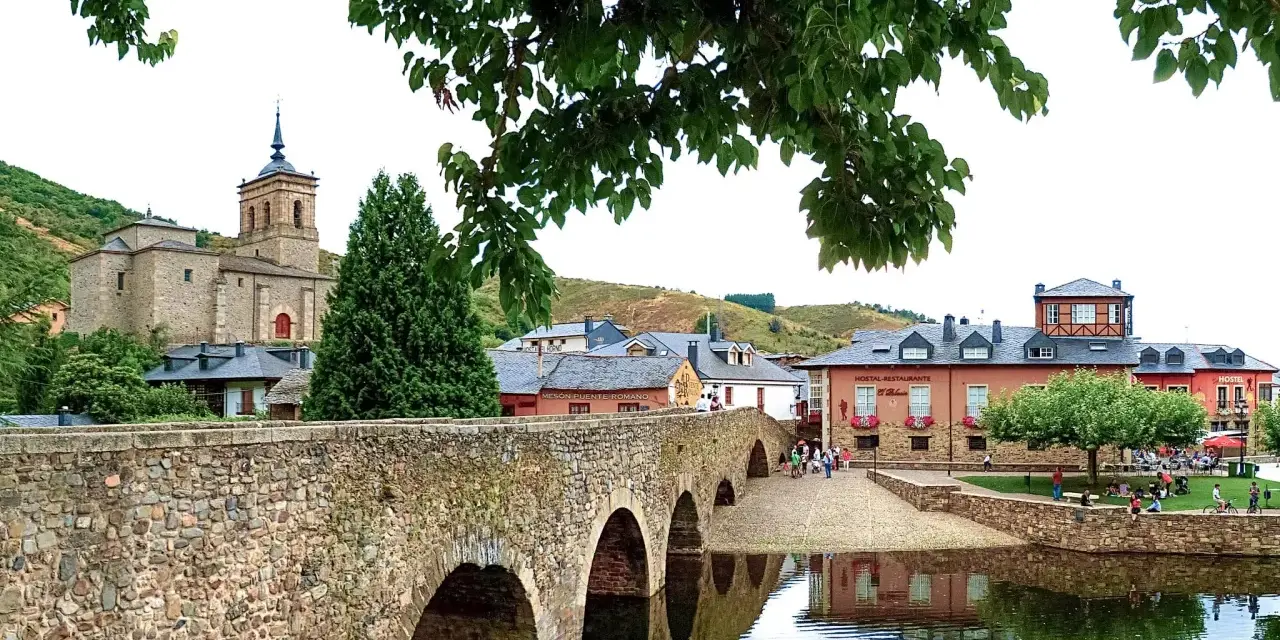 Puente romano y el pueblo de Molina Seca que ver. Iglesia antigua, casas y río con reflejos.