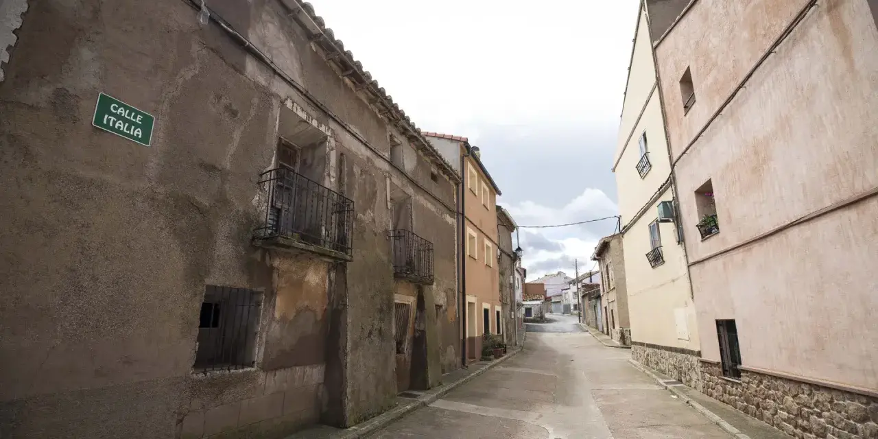 Calle Italia en Villar del Salz, un pueblo con casas antiguas y un cielo nublado.