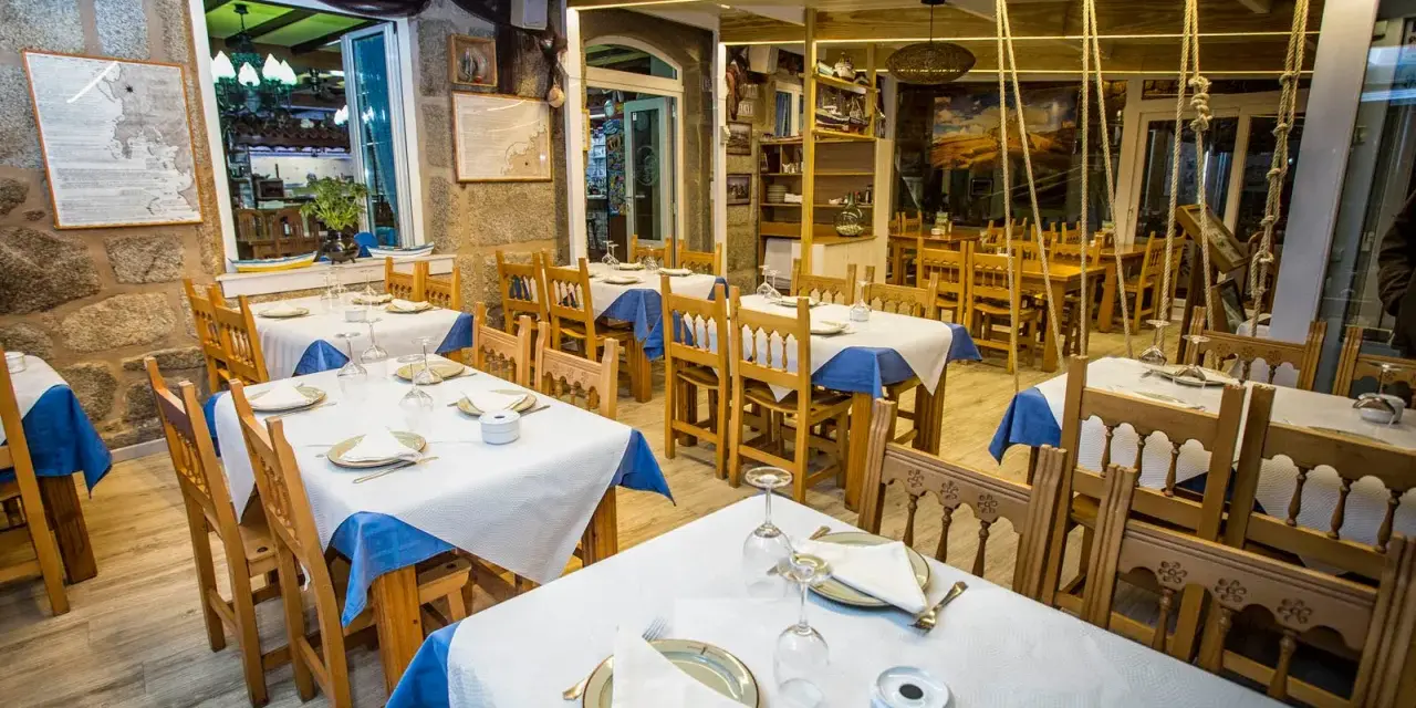 Mesas puestas y listas para comer en Muxía. Ambiente acogedor con decoración marinera, perfecto para disfrutar de la gastronomía local.