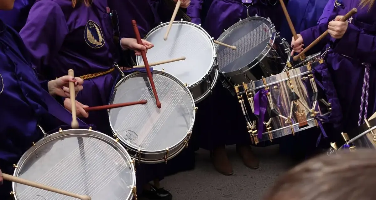 Tambores resonando, parte de las tradiciones de Aragón. Nazarenos con túnicas moradas golpean los parches en una procesión.