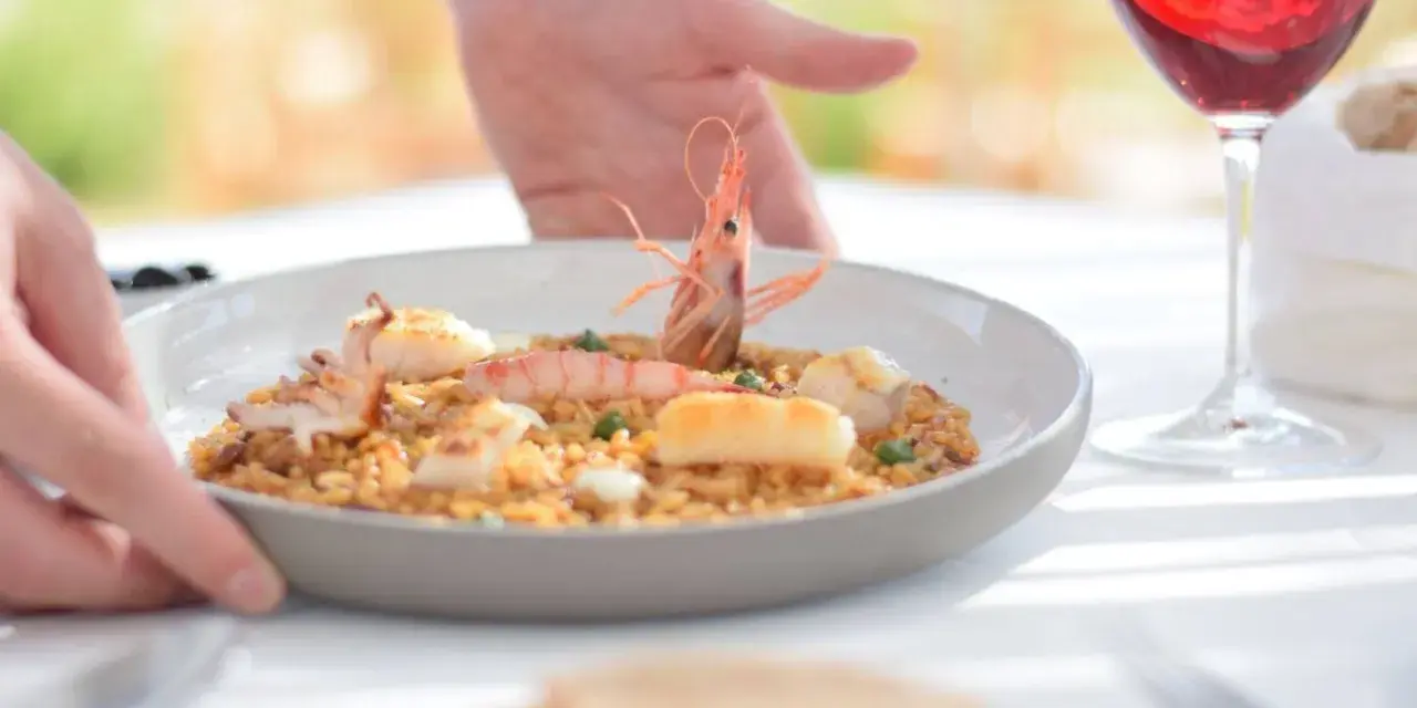 Un plato de paella de marisco servido con vino tinto, ideal para saber donde comer en Menorca.