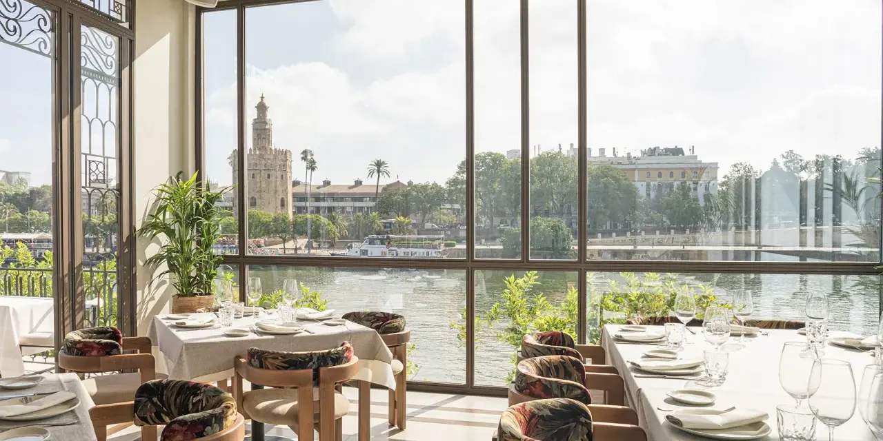 Mesas elegantemente puestas con vistas a la Torre del Oro. Un lugar ideal para disfrutar de una experiencia culinaria en el mejor restaurante Sevilla.