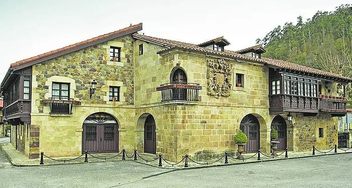 Edificio histórico de piedra con balcones de madera, ideal para saber donde comer en Lierganes.