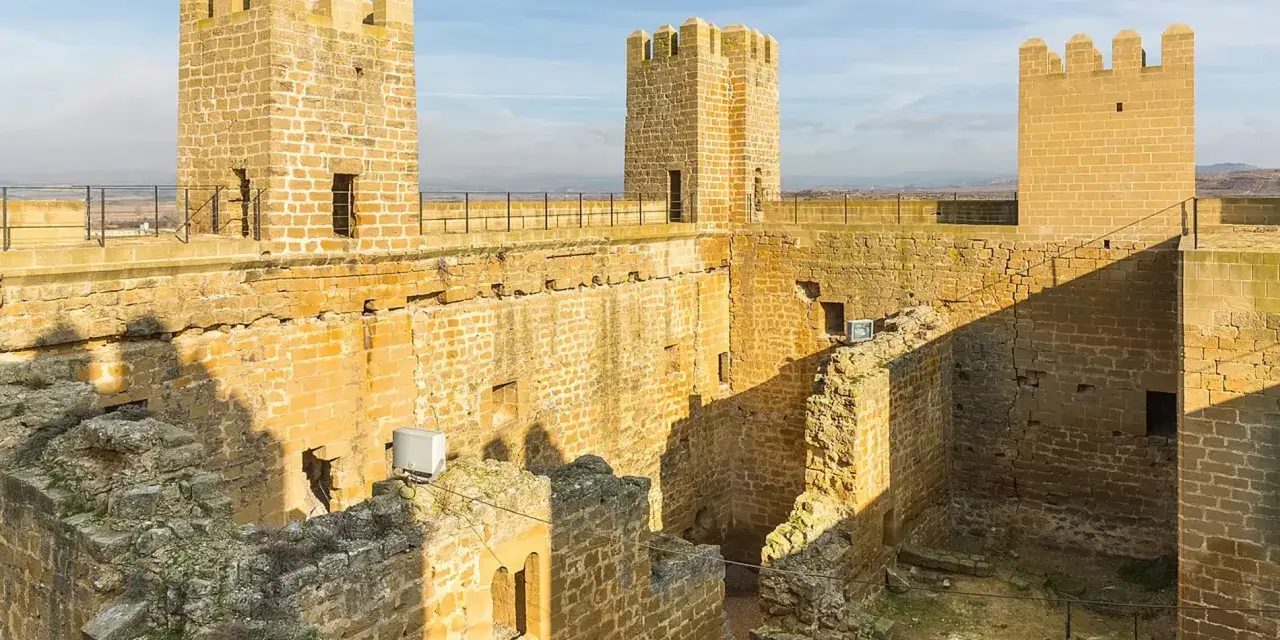 El castillo de Sádaba, con sus imponentes torres de piedra dorada, se alza bajo un cielo azul, invitando a imaginar batallas y leyendas.