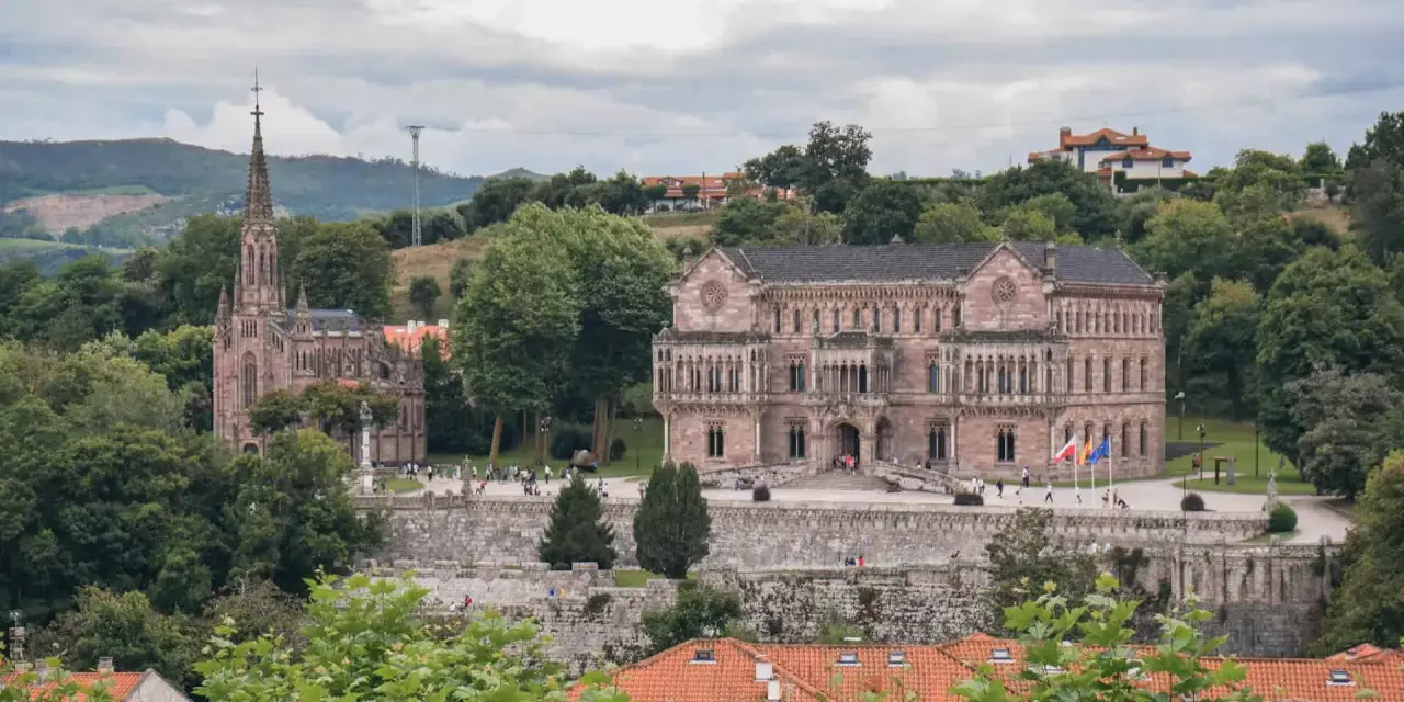 Edificio neogótico y palacio en Comillas, rodeados de vegetación y colinas. Un lugar para ver y disfrutar.