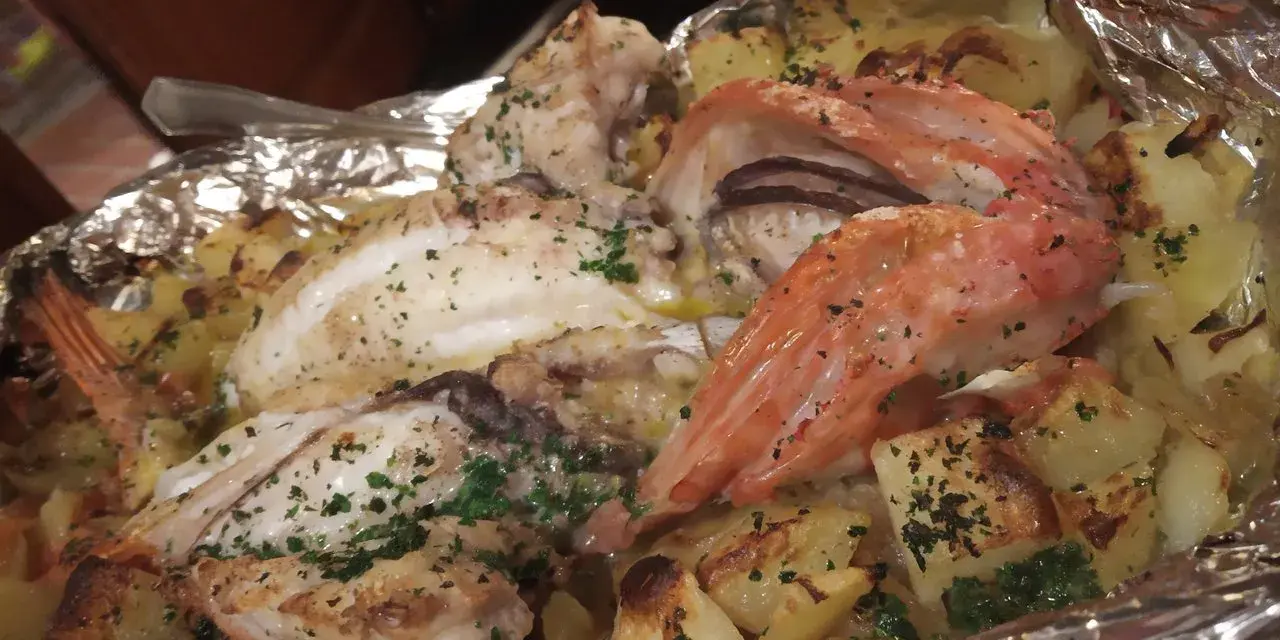 Delicioso pescado y gambas al horno con patatas, un plato típico de la casa Juanita Begur.