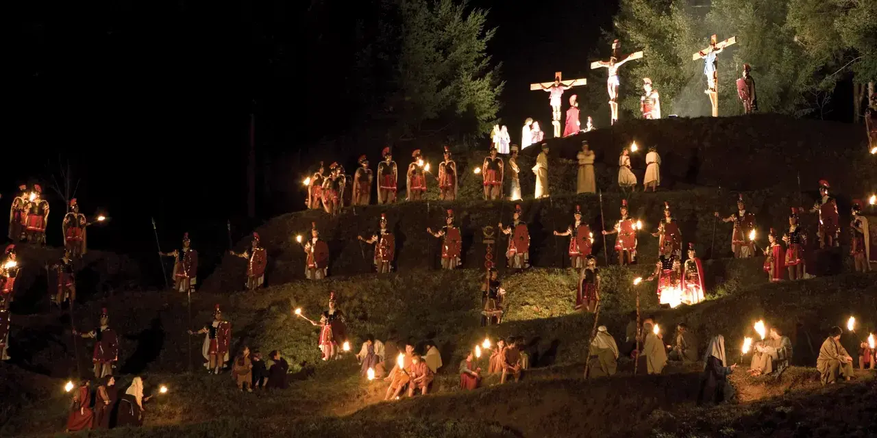 Representación nocturna del vía crucis en Sant Hilari, con antorchas iluminando a soldados romanos y figuras bíblicas en una ladera.