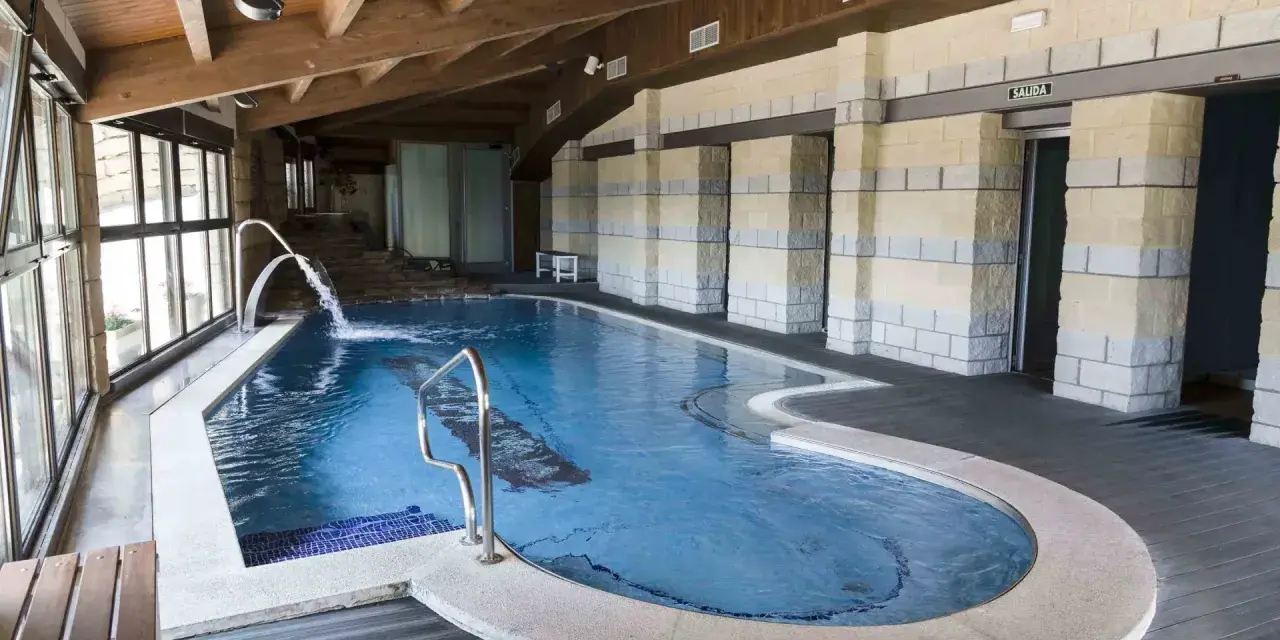 Piscina interior con cascadas y escaleras de piedra, ideal para relajarse en las **Vilas del Turbon**.