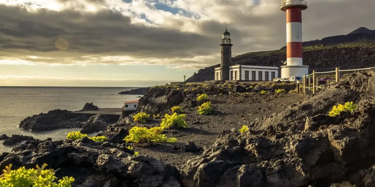 Faros gemelos en la costa rocosa, un destino que ver en La Palma. El mar y el cielo nublado completan la escena.