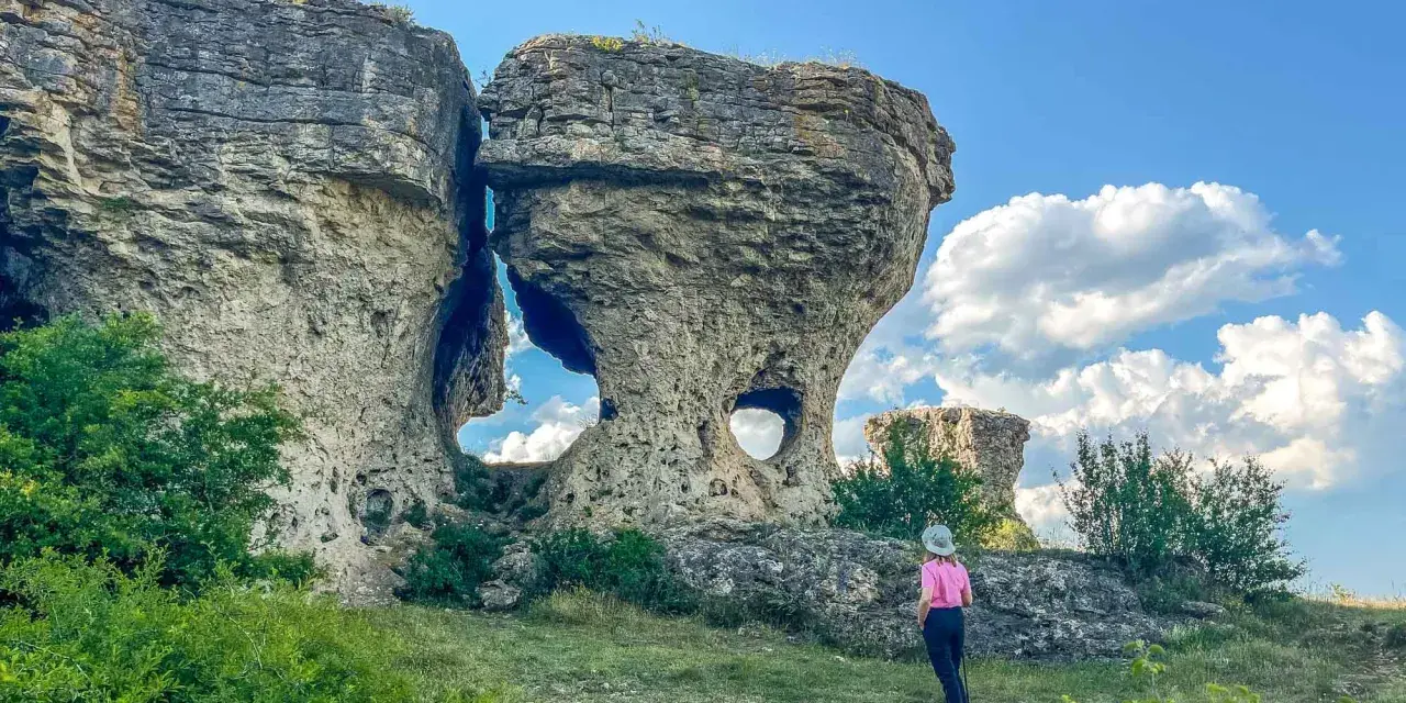 Una persona observa formaciones rocosas únicas, como si fueran las tuerces ruta circular, bajo un cielo azul con nubes.