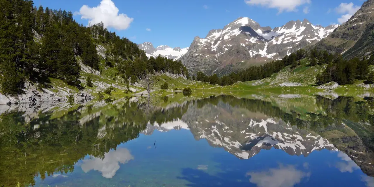 Espectacular reflejo de montañas nevadas y bosques en un lago sereno. Un lugar ideal que ver en el Pirineo Aragonés para conectar con la naturaleza.