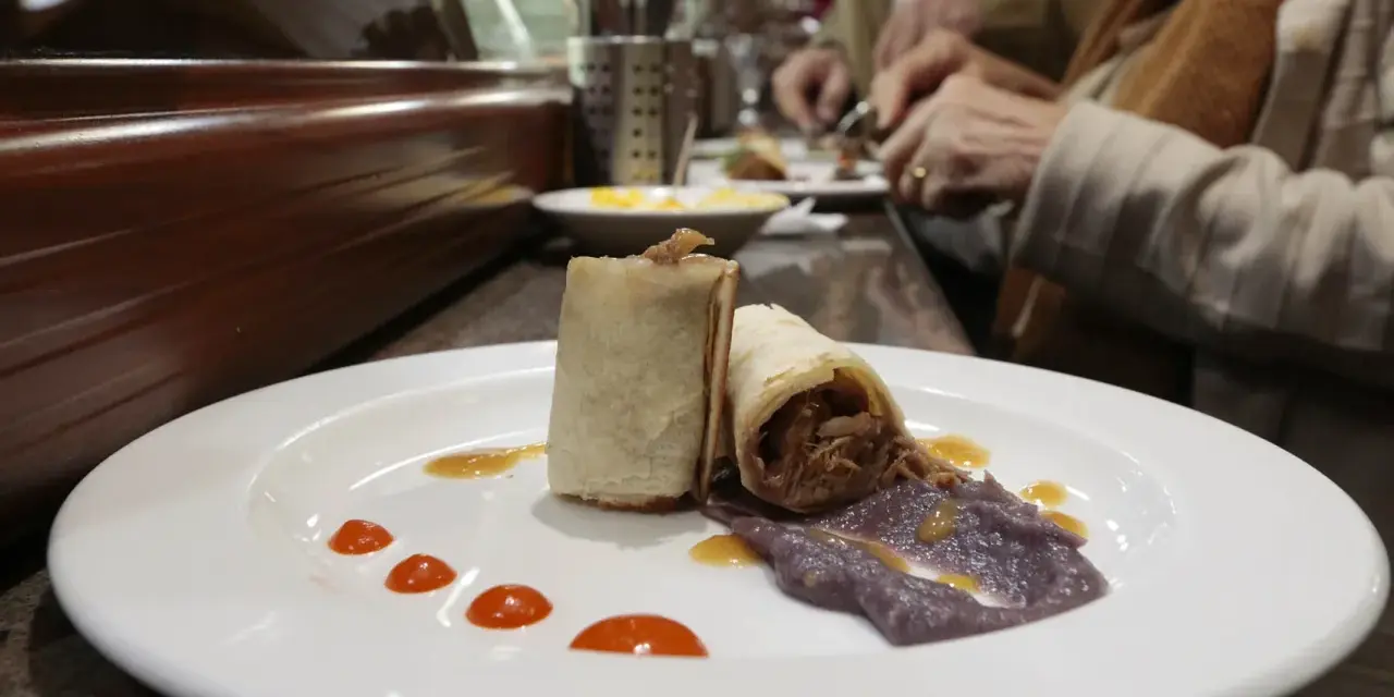 Dos rollitos de carne deshebrada con puré morado y salsa, un delicioso bocado para comer en Plasencia.