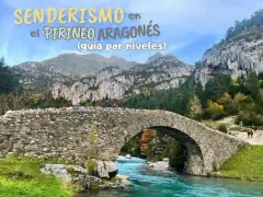 Puente de piedra sobre río turquesa en la montaña de Pirineos. Senderismo en el Pirineo Aragonés.