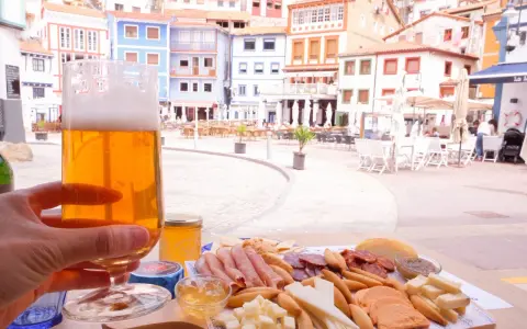 Disfrutando de una cerveza y una tabla de quesos y embutidos en Cudillero, con las coloridas casas de fondo.